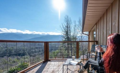 a woman sitting on a balcony looking out at the mountains at Happy Trails Stunning Smoky Mtn Views Hot Tub Game Room Resort Pools in Gatlinburg