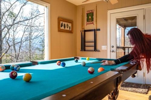 a woman playing pool in a living room at Happy Trails Stunning Smoky Mtn Views Hot Tub Game Room Resort Pools in Gatlinburg