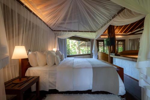 a bedroom with a white bed with a canopy at Hotel e Resort Villas de Trancoso in Trancoso