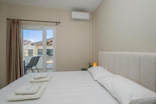 a white bedroom with a bed and a balcony at Athena's Studios 2 in Polychrono