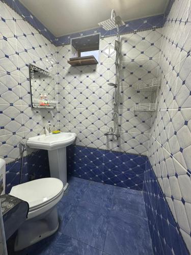 a blue and white bathroom with a toilet and a sink at Khan House in Sheki