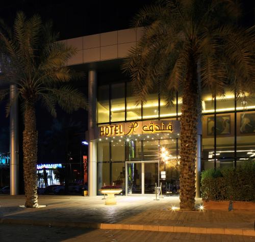 a building with two palm trees in front of it at Qaser Alhamra Hotel Riyadh in Riyadh