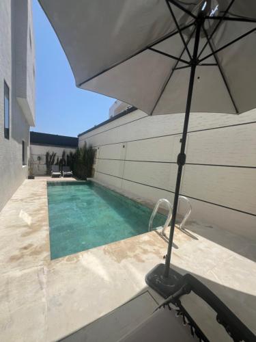 an umbrella sitting next to a swimming pool at Villa 4 chambres avec piscine in Tangier