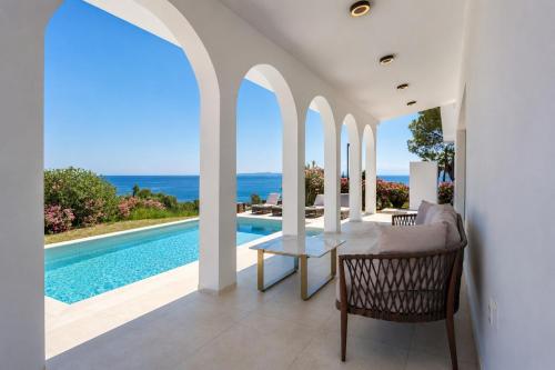 a dining room with a table and a swimming pool at Xenia Sea view Villa in Argassi