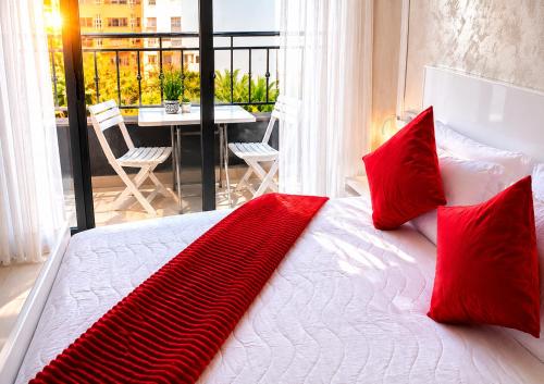 a bedroom with a bed with red pillows and a balcony at Nador Skyline Al Matar in Nador