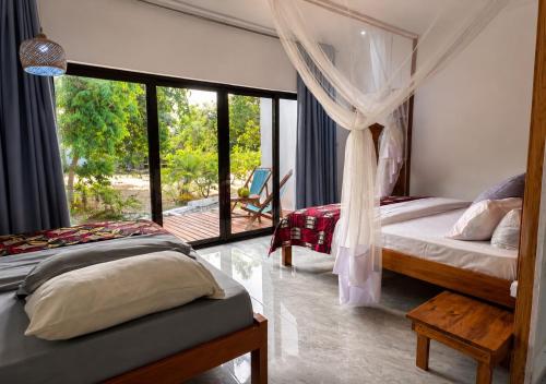 a bedroom with two beds and a large window at CosyBe Villas in Praia do Tofo