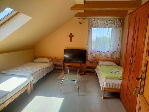 a small room with two beds and a tv at Bella Vendégház in Székesfehérvár