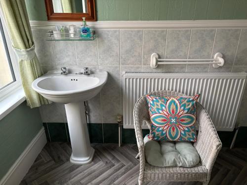 a bathroom with a sink and a chair with a pillow at Weybourne Guest House in Tenby