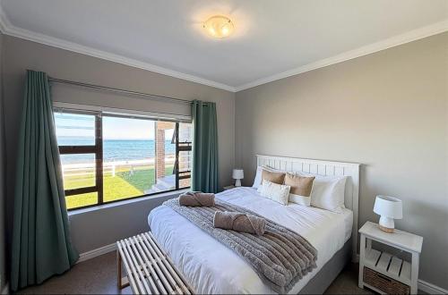 a bedroom with a large bed with a large window at Franskraal Zeehoek in Franskraalstrand