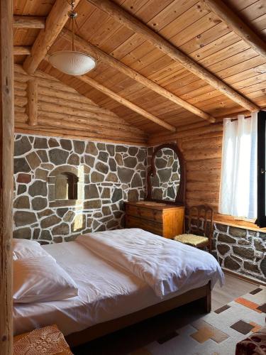 a bed in a room with a stone wall at Lodges VEIS in Kamenicë