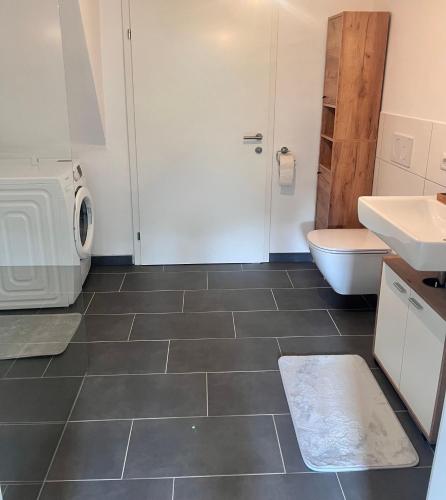 a bathroom with a toilet sink and a washing machine at Ferienhaus Michi in Ursprung