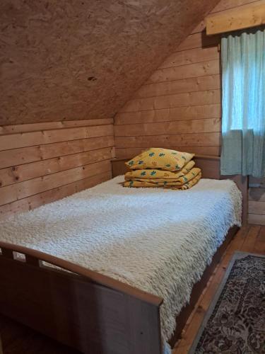 a bed in a wooden cabin with two pillows on it at Huntingbox in Purila