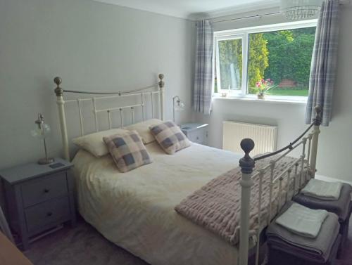 a bedroom with a bed with pillows and a window at 2 Bedroom Garden Flat in Halesworth