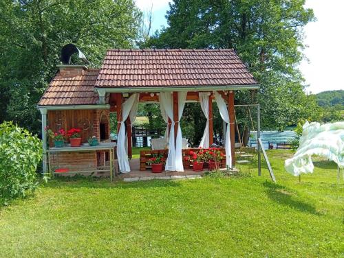 a small gazebo with flowers in a yard at Kuća za odmor Una in Dvor