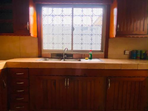 a kitchen with a sink and a window at Home & Heart Gambia in Brusubi