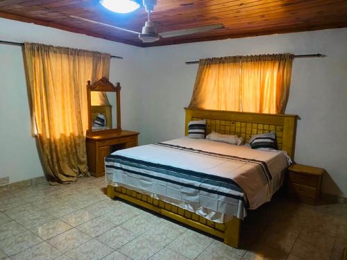 a bedroom with a bed and two windows and a mirror at Home & Heart Gambia in Brusubi