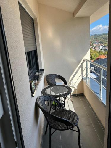 a balcony with two chairs and a table on it at Apt Moravica in Soko Banja