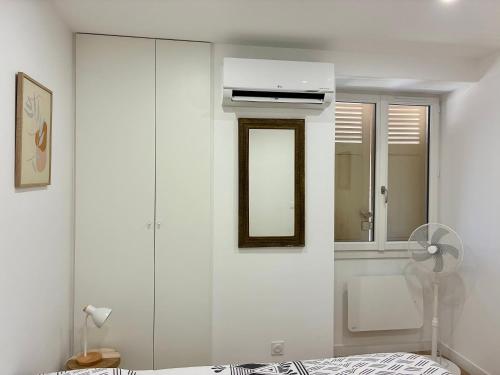 a white bedroom with a mirror and a bed at Le Vinois Climatisation 2 chambres balcon in Vinay