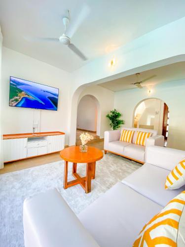 a living room with white furniture and a flat screen tv at 9 bedroom Villa in Mombasa