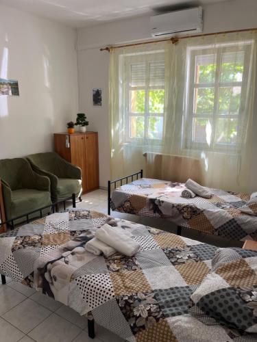a room with three beds and a chair and a window at Mazsola apartman in Hódmezővásárhely