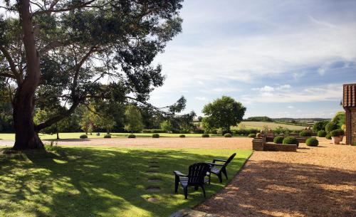 two benches sitting in the grass under a tree at Luxury Escape in Hunstanton