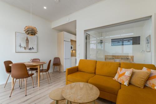 a living room with a yellow couch and a table at Apartment Aurinkoranta D5 saunallinen kaksio merinäkymällä Kalajoki in Kalajoki