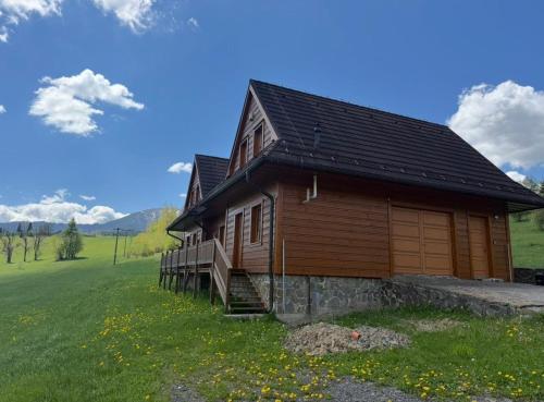 a wooden house in a field with a grassy field at Chalet Mates in Ždiar