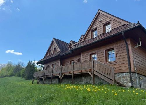 a large wooden house with a porch on a green field at Chalet Mates in Ždiar