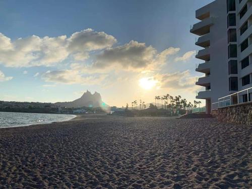 a view of a beach with a building and the ocean at By the sea Condominium in San Carlos