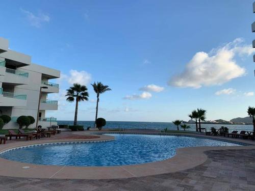 a swimming pool next to a building and the ocean at By the sea Condominium in San Carlos