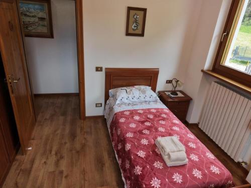 a small bedroom with a bed with a red blanket at Winter and Summer Cortina in Cortina dʼAmpezzo