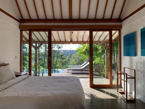 a bedroom with a bed and large glass doors at Villa YAMI Uluwatu Private Infinity Pool Jungle Views in Ungasan
