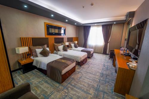 a hotel room with two beds and a television at Erbil Quartz Hotel in Erbil