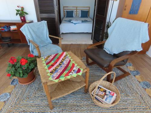 a living room with a chair and a table and a bed at Minha Alegre Casinha in Sines