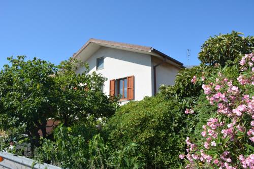 a white house with trees and pink flowers at Casa Argi in Camerano
