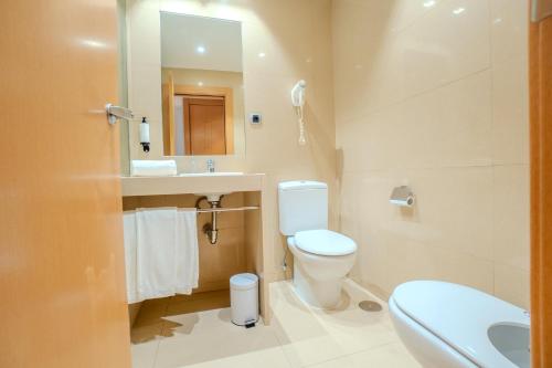 a bathroom with a toilet and a sink and a mirror at Hotel Reston Valdemoro in Valdemoro