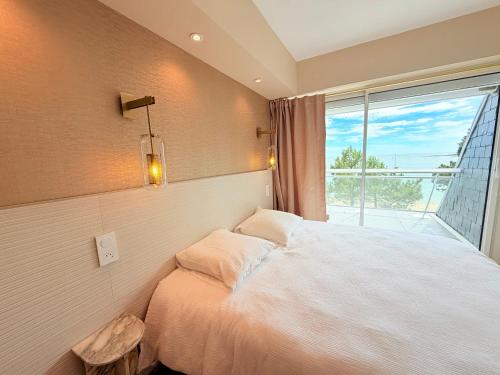 a bedroom with a bed and a large window at Escale élégante à la mer Duplex neuf en front de mer in Bénodet