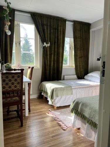 a bedroom with two beds and a desk and a window at Sköna Rum Fryksta in Kil