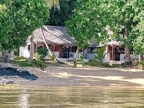 a house with a thatched roof next to a river at Hôtel La Baleine in Sainte Marie