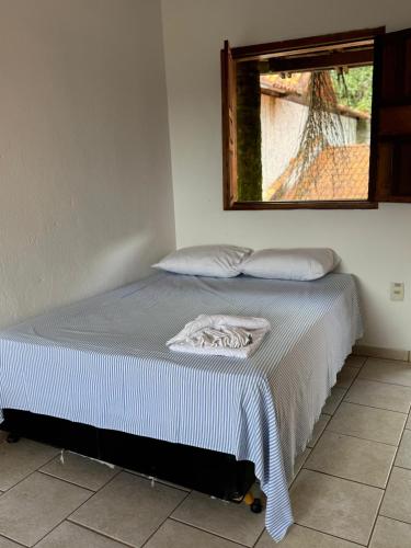 a bed in a room with a window at Pousada das Cores Cocais in Barão de Cocais