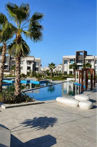 a resort with a swimming pool with palm trees and buildings at GAIA Penthouse in El Dab‘a
