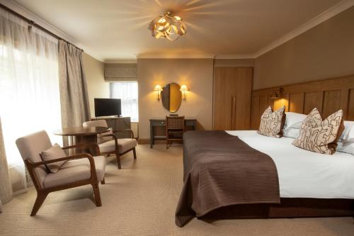 a hotel room with a large bed and a chair at Budock Vean Hotel and Spa in Falmouth