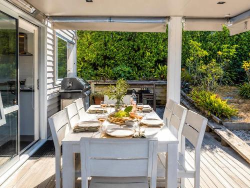 a white table and chairs on a patio with a grill at Bella Seven- Stay Waiheke in Oneroa