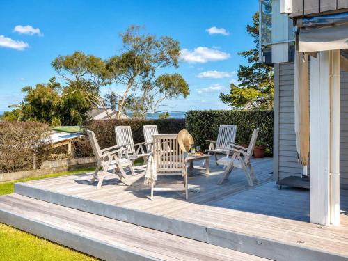 a deck with chairs and a table on a house at Bella Seven- Stay Waiheke in Oneroa