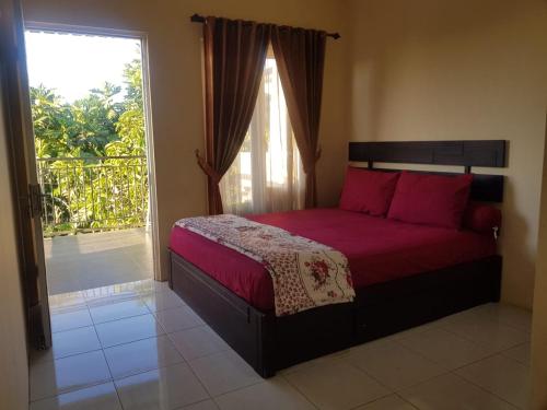 a bedroom with a bed with red sheets and a window at Villa Batu Iggy in Batu