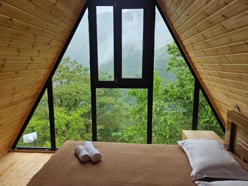 a bedroom in a tree house with a large window at Machaxela Skyline in Tsʼkhemlisi