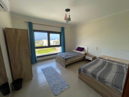 a bedroom with two beds and a window at GAIA Penthouse in El Dab‘a