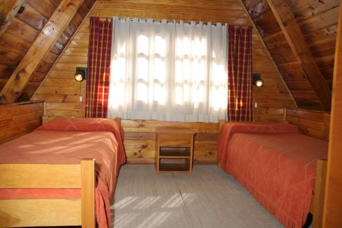 a room with two beds and a window in a cabin at Complejo Villa Azul in Esquel