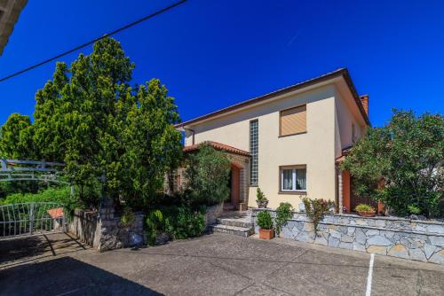 a house with a stone retaining wall and trees at Room Marta in Omišalj