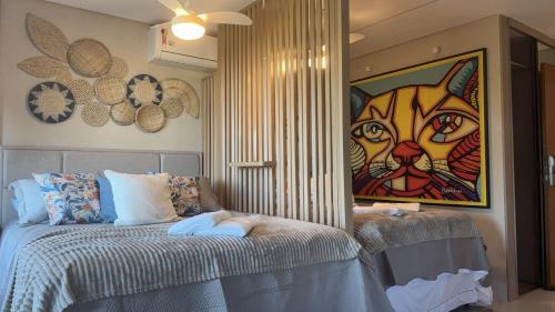 a bedroom with a bed with a painting of a cat at Marulhos resort Muro Alto flats Premium frente ao mar in Porto De Galinhas